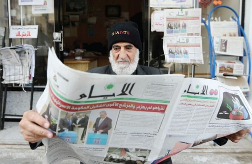A Gaza man reads a newspaper, featuring the Israeli election on its front page, in Khan Younis, March 18. (photo credit: IBRAHEEM ABU MUSTAFA / REUTERS)