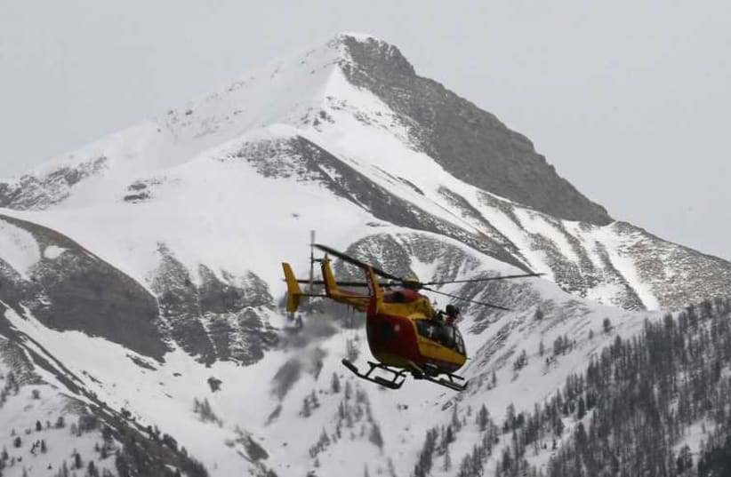 A rescue helicopter from the French Securite Civile flies over the French Alps during a rescue operation near the crash site of an Airbus A320. (photo credit: REUTERS)
