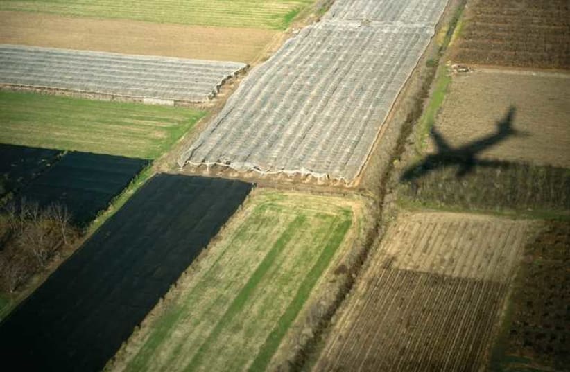 A plane flies over a field (ILLUSTRATIVE) (photo credit: REUTERS)