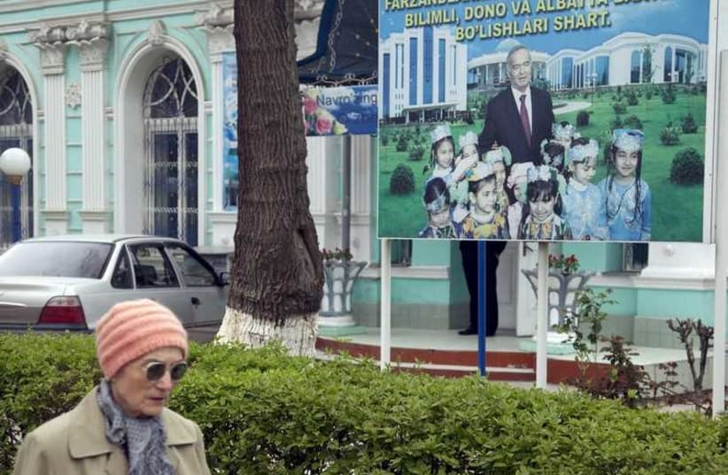 A woman walks past an election board of Uzbekistan's President and presidential candidate Islam Karimov near a polling station in Tashkent March 29 (photo credit: REUTERS)