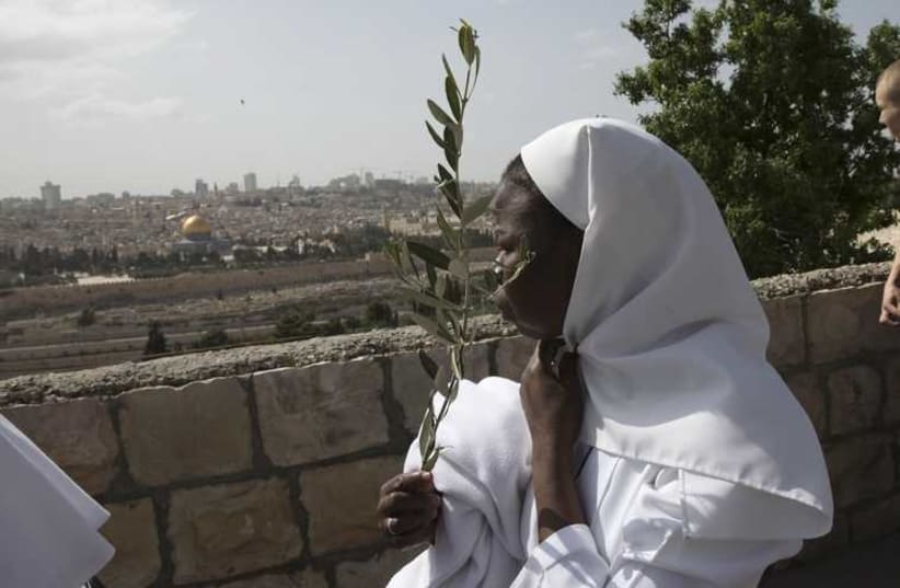 A Catholic nun holds an olive branch during a Palm Sunday procession on the Mount of Olives in Jerusalem  (photo credit: REUTERS)