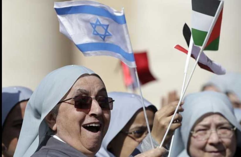 Nuns wave Israeli and Palestinian flags before Pope Francis arrives to lead the general audience in St. Peter's Square at the Vatican (photo credit: REUTERS)