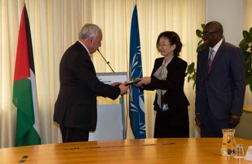 ICC Second Vice-President Judge Kuniko Ozaki, in the presence of the President of the Assembly of States Parties, H.E. Sidiki Kaba, presents Palestinian Authority Foreign Minister Riad Al-Malki with a special edition of the Rome Statute  (photo credit: ICC)