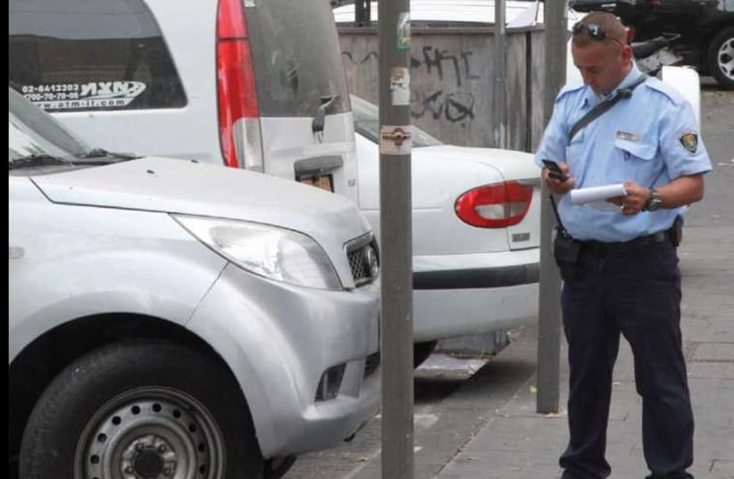 An inspector issues a parking ticket on Hillel Street. (photo credit: MARC ISRAEL SELLEM/THE JERUSALEM POST)