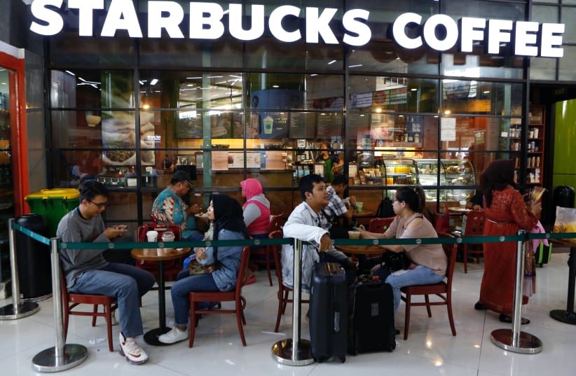 Customers sit outside of a Starbucks cafe in Jakarta, Indonesia July 1, 2017. (photo credit: REUTERS)