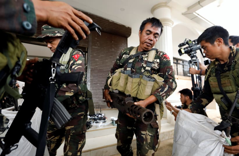 Philippines army soldiers store seized combat weapons in bags as government troops continue their assault against insurgents in Marawi city, Philippines July 4, 2017.  (photo credit: REUTERS/JORGE SILVA)