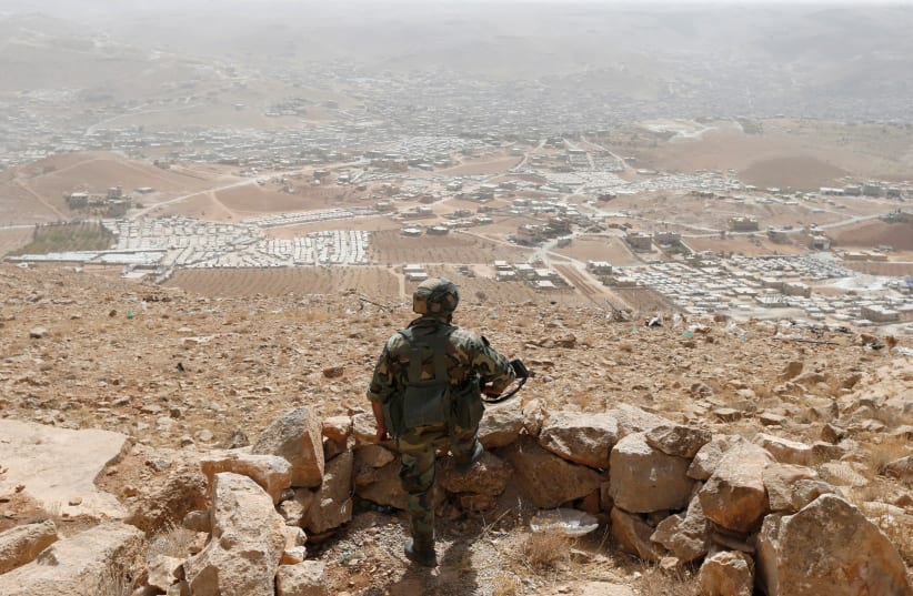 A Lebanese soldier carries his weapon as he stands at an army post in the hills above the Lebanese town of Arsal, near the border with Syria, Lebanon September 21, 2016. Picture taken September 21, 2016.  (photo credit: MOHAMED AZAKIR / REUTERS)