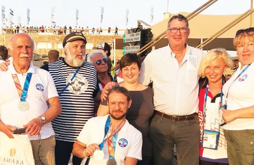 Konstantin Afinogenov (center) shows his Maccabiah medals with fellow team members, Maccabi World Union Executive Director Eyal Tiberger and GPF Deputy CEO Sana Britavsky. (photo credit: Courtesy)