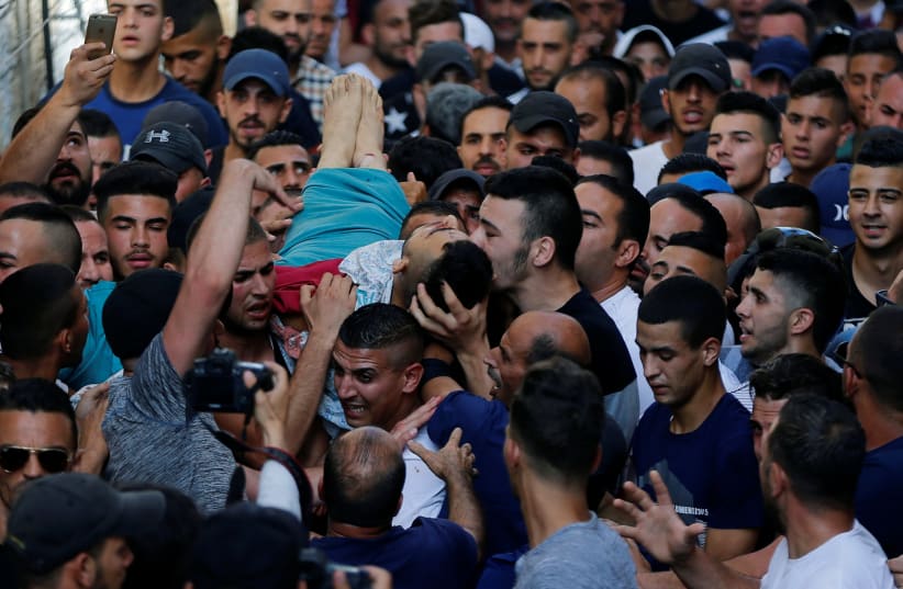 A mourner kisses the body of Palestinian Mohammad Abu Ghannam during his funeral in the east Jerusalem neighbourhood of A-tur July 21, 2017. (photo credit: AMMAR AWAD/REUTERS)