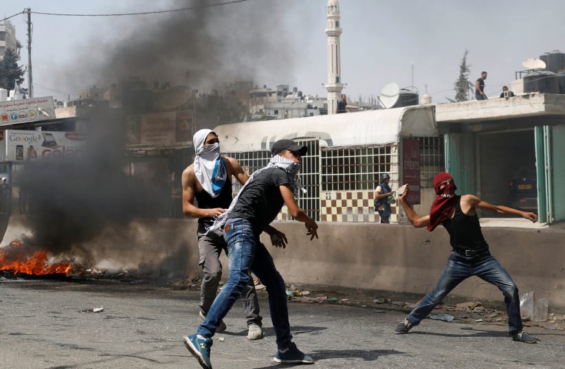 Palestinian protesters hurl stones towards Israeli troops during clashes near Qalandiya checkpoint near the West Bank city of Ramallah (photo credit: REUTERS/MOHAMAD TOROKMAN)