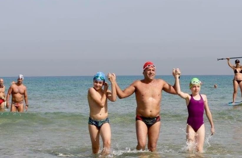 Guy Cohen at the end of his 24-hour Swim from the Heart in Haifa, on the beach with his children Matan and Noa. (photo credit: GUY COHEN)