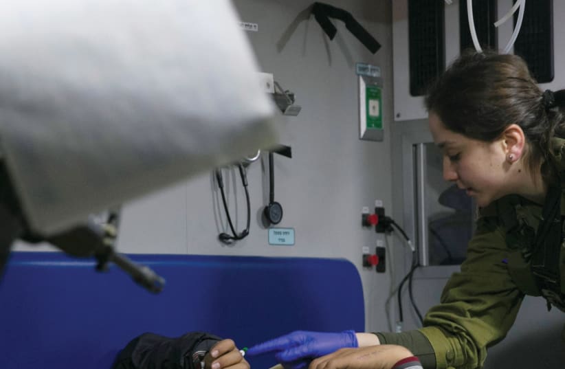 An IDF medic administers initial treatment to a wounded Syrian in a military ambulance near the Israeli-Syrian border (photo credit: REUTERS)