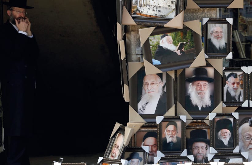 AN ULTRA-ORTHODOX man stands near a display of pictures of rabbis and religious leaders for sale outside a shop in Jerusalem’s Mea She’arim neighborhood. (photo credit: REUTERS)