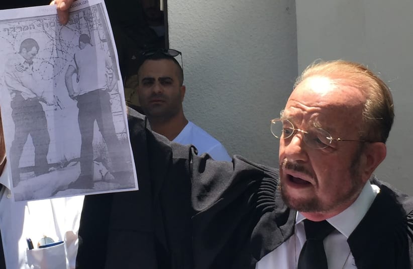 Elor Azaria's attorney Sheftel holding up a sign of a similar incident which took place in 2002, July 30, 2017. (photo credit: ANNA AHRONHEIM)
