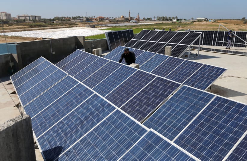 A worker installs solar panels on a roof in Gaza City (photo credit: IBRAHEEM ABU MUSTAFA / REUTERS)