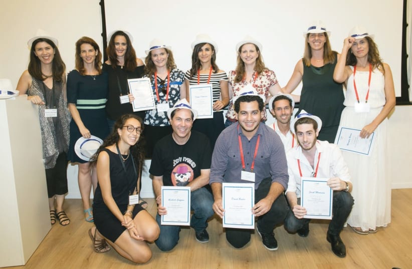 Newly minted graduates of TheNest’s second cohort of small-business owners pose with their certificates of completion and graduation caps at Wix headquarters in the Tel Aviv Port (photo credit: SASHA PRILUTSKY/DVISION)