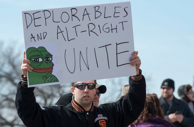 An alt-right protestor holds a sign depicting Pepe the Frog, a cartoon associated with the movement (photo credit: Wikimedia Commons)