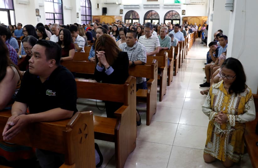 Local residents pray during a Sunday mass at Sta Barbara Church on the island of Guam, a US Pacific Territory, August 13, 2017. (photo credit: ERIC DE CASTRO/ REUTERS)