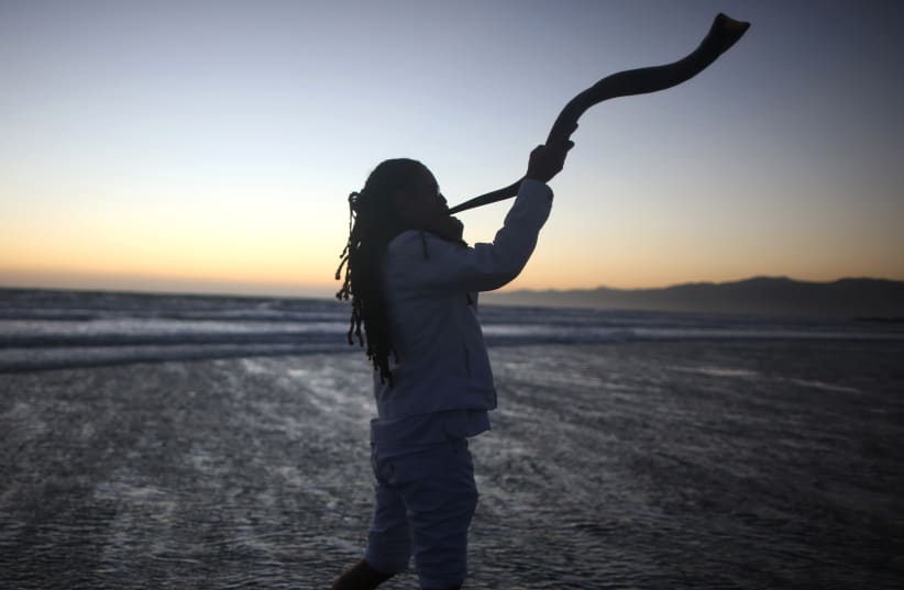 A young man plays the shofar during the Nashuva Spiritual Community Jewish New Year celebration  (photo credit: LUCY NICHOLSON / REUTERS)