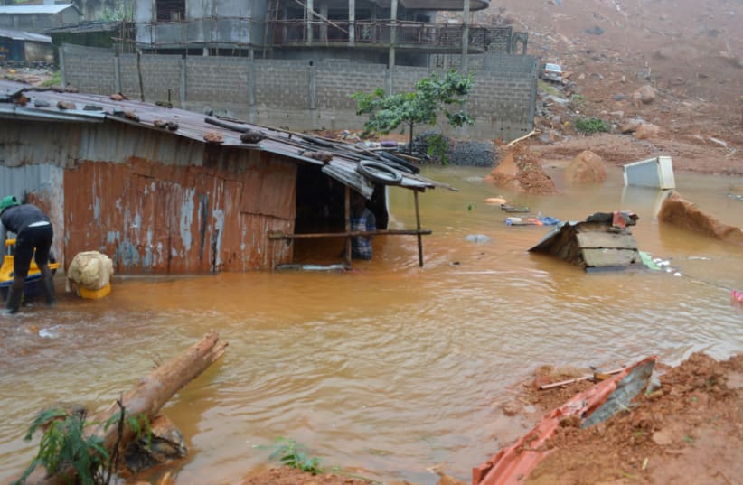 Residents save belongings in floodwaters after a mudslide in the mountain town of Regent, Sierra Leone August 14, 2017.  (photo credit: ERNEST HENRY / REUTERS)