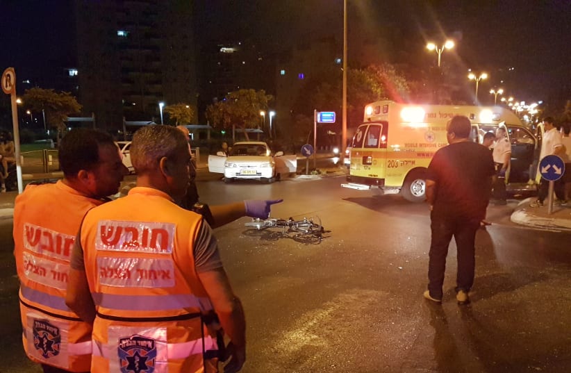 Two United Hatzalah volunteers assess the scene of an accident involving a bicyclist and a van (photo credit: BECKY BROTHMAN)