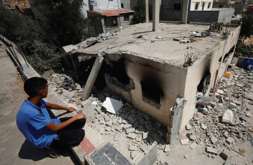 A boy looks at the family house of terrorist Adel Ankush in the village of Deir Abu-Mashal after it was demolished yesterday by the IDF using a controlled explosion.  (photo credit: MOHAMAD TOROKMAN/REUTERS)