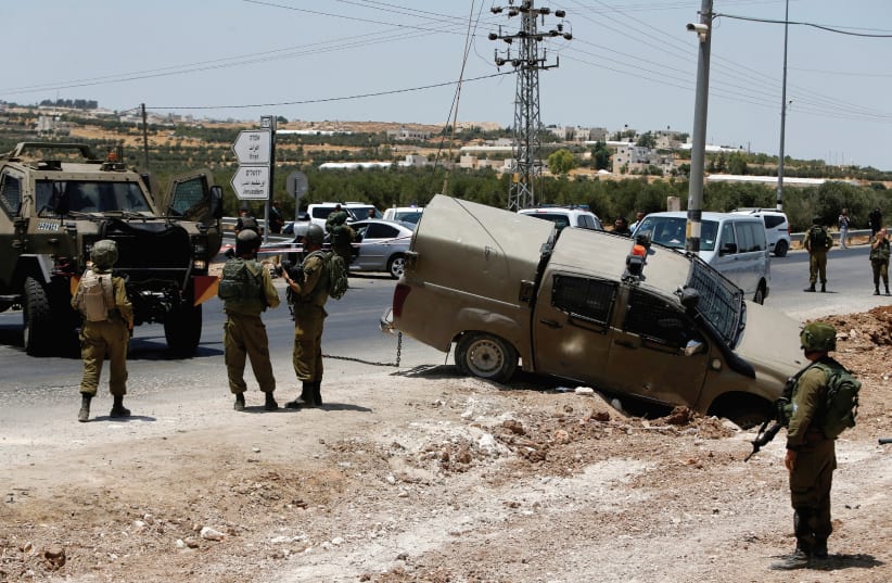 Soldiers stand guard at the scene of a car ramming and stabbing attack at the Tekoa checkpoint in the West Bank near Bethlehem in July. (photo credit: REUTERS)