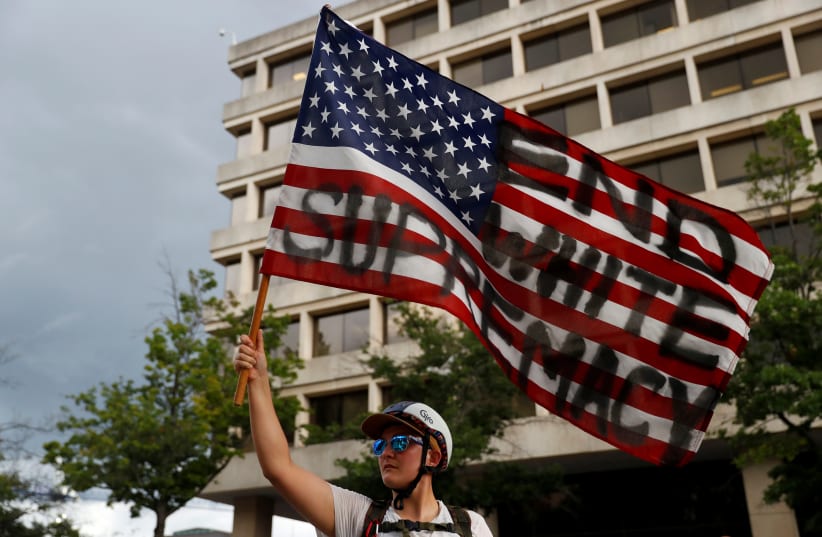 A demonstrator holds an American flag during a protest calling for the removal of the statue of Confederate General Albert Pike in Washington, U.S., August 18, 2017 (photo credit: REUTERS/AARON P. BERNSTEIN)