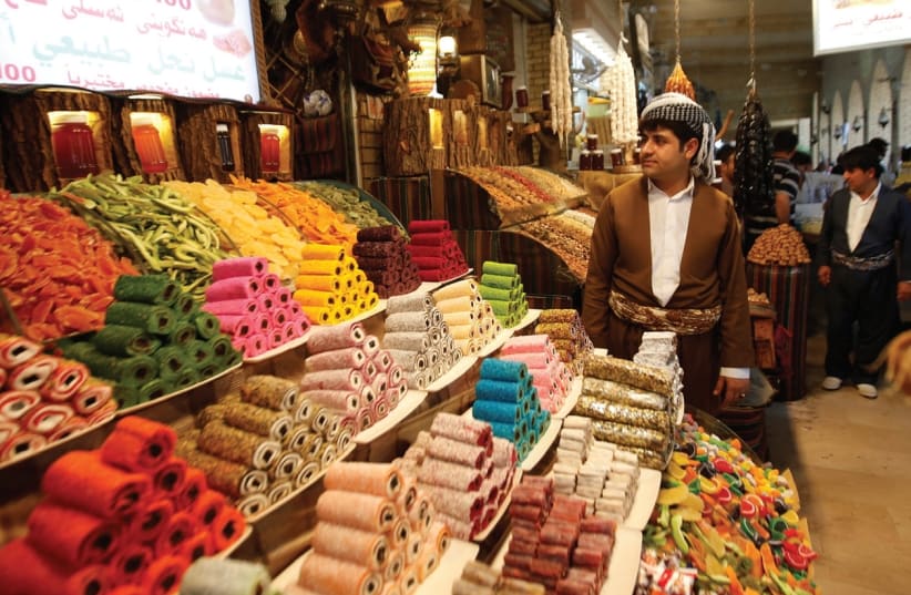 A KURDISH MAN sells sweets at a market in Erbil, the capital of Iraq’s Kurdistan region. (photo credit: AZAD LASHKARI / REUTERS)
