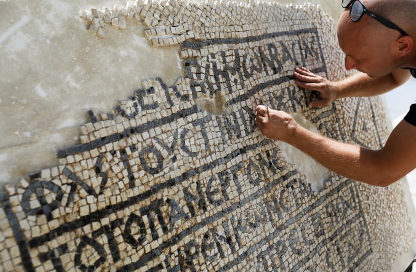 A conservationist works on a 1500-year-old mosaic floor bearing a Greek writing, discovered near Damascus Gate in Jerusalem's Old City, as it is displayed at the Rockefeller Museum in Jerusalem August 23, 2017. (photo credit: REUTERS/Ronen Zvulun)