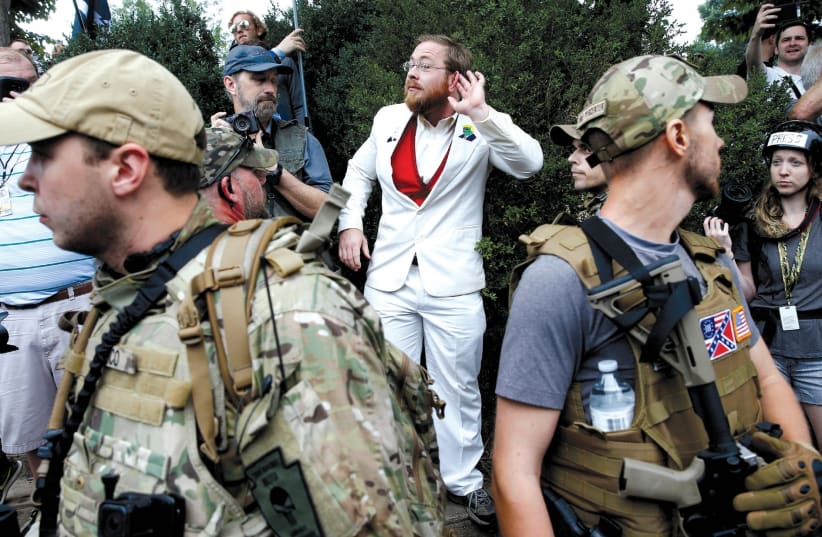 A WHITE nationalist stands behind militia members after he scuffled with a counter demonstrator in Charlottesville, Virginia, August 12. (photo credit: JOSHUA ROBERTS / REUTERS)