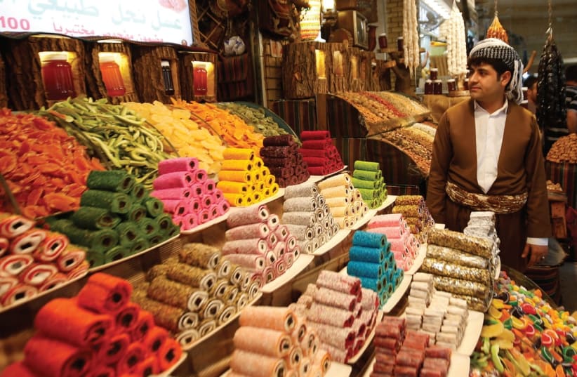 A KURDISH MAN sells traditional candies at market in Erbil, Iraq. (photo credit: REUTERS)