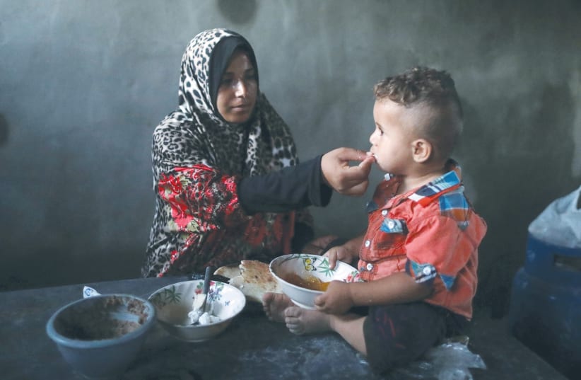 A Palestinian woman feeds her son last month during a power cut in Khan Yunis. (photo credit: MOHAMMED SALEM/ REUTERS)