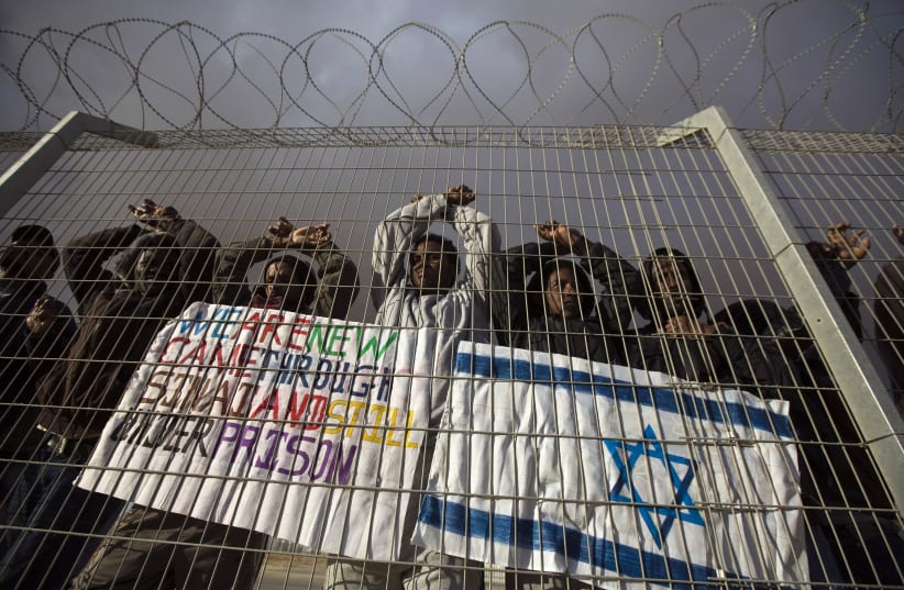 African migrants gesture behind a fence during a protest against Israel's detention policy towards them (photo credit: AMIR COHEN - REUTERS)