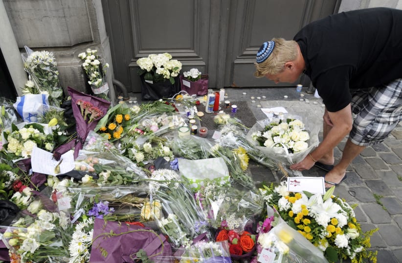 A passer-by puts down flowers at the entrance of the Jewish Museum, site of a shooting in central Brussels May 25, 2014. (photo credit: REUTERS)