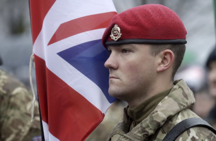 A British Army soldier stands near his national flag, November 18, 2015 (photo credit: REUTERS)