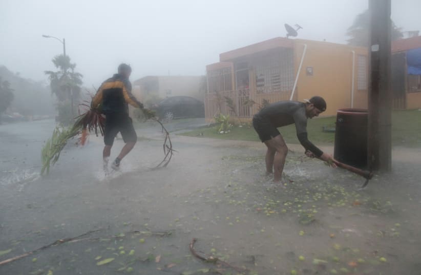 People pick up debris as Hurricane Irma howled past Puerto Rico after thrashing several smaller Caribbean islands, in Fajardo, Puerto Rico September 6, 2017. (photo credit: REUTERS)