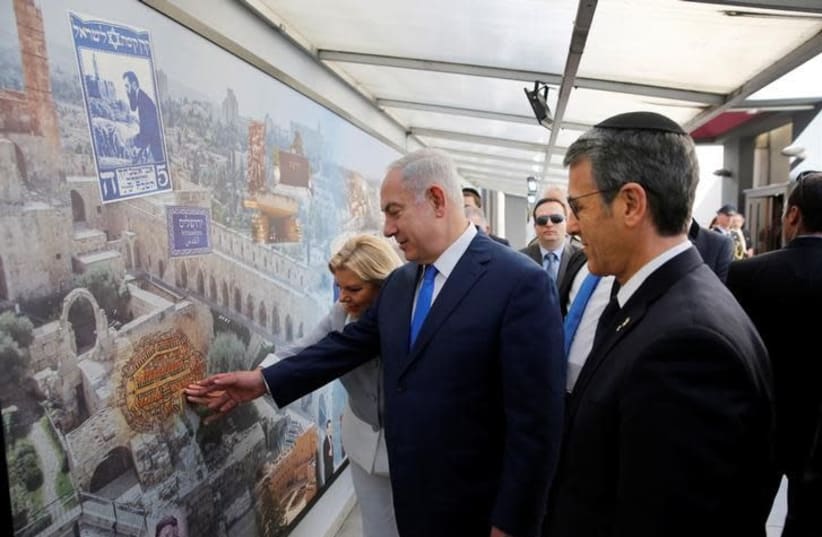 Israeli Prime Minister Benjamin Netanyahu and his wife Sara touch a mural alongside Agustin Zbar, President of the Argentine Israeli Mutual Association (AMIA) Jewish community center, as they visit the AMIA building, which was bombed in 1994, in Buenos Aires, Argentina September 11, 2017. Embassy of (photo credit: HANDOUT/REUTERS)