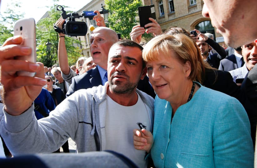 A migrant takes a selfie with German Chancellor Angela Merkel outside a refugee camp near the Federal Office for Migration and Refugees after registration at Berlin's Spandau district, Germany September 10, 2015 (photo credit: REUTERS/FABRIZIO BENSCH)