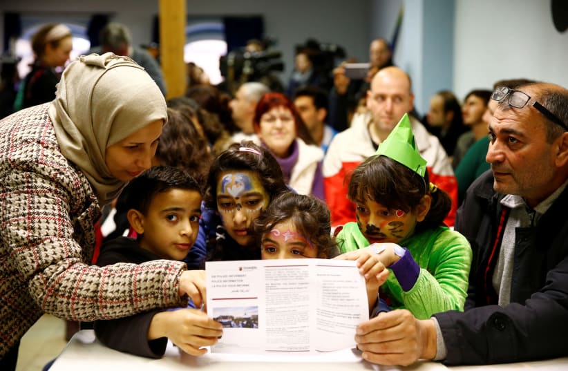 A Syrian family from Palmyra, including children with carnival costumes, read an information leaflet advising on social etiquette for refugees ahead of the carnival season, at a refugee camp in Mainz, Germany February 1, 2016 (photo credit: REUTERS/KAI PFAFFENBACH)