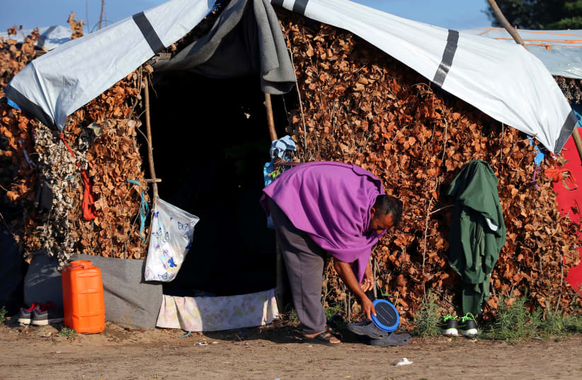A refugee cleans his tent in a makeshift camp on the Hungary-Serbia border, on the Serbian side of a transit zone set up by Hungarian authorities to filter refugees at Roszke, Hungary, September 2, 2016. Picture taken September 2, 2016 (photo credit: REUTERS/LASZLO BALOGH)