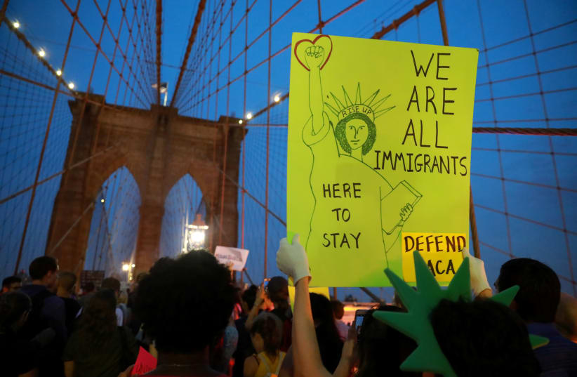 People march across the Brooklyn Bridge to protest the planned dissolution of DACA (photo credit: STEPHEN YANG / REUTERS)