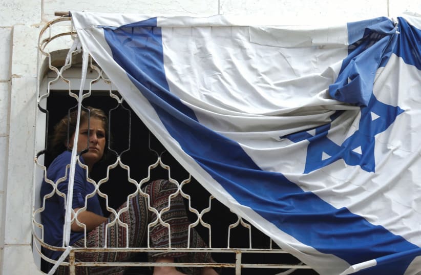 A YOUNG Jewish settler in Hebron looks out of a window in a disputed building. (photo credit: AMIR COHEN - REUTERS)