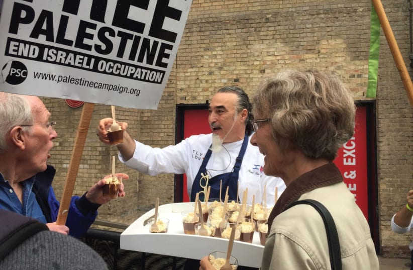 CHEF SHAUL Ben Aderet offers chocolate mousse to BDS protesters outside the Roundhouse Theatre. (photo credit: SHAHAR AZRAN)