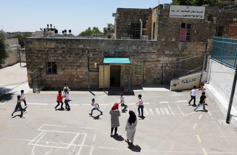 Palestinian children play on a court at a school in the East Jerusalem neighbourhood of Silwan June 19, 2017. Picture taken June 19, 2017. (photo credit: REUTERS/AMMAR AWAD)