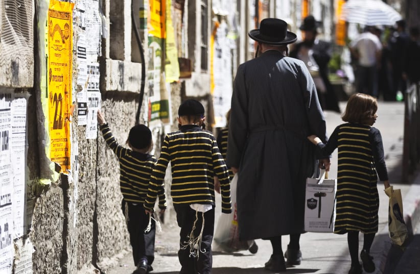An ultra-Orthodox Jewish man walks with his children on a street in Jerusalem's Mea Shearim neighbourhood September 24, 2015. (photo credit: REUTERS)