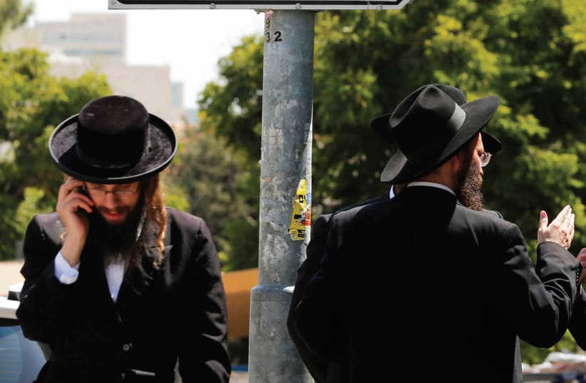 ULTRA-ORTHODOX MEN walk past the entrance to an IDF draft office in Jerusalem. (photo credit: REUTERS)
