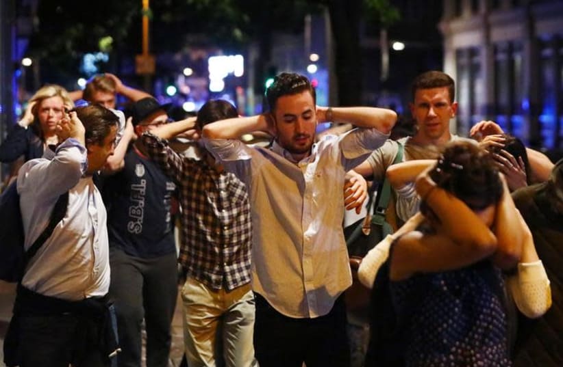 People leave the London Bridge area with their hands up after a terrorist attack (photo credit: NEIL HALL/REUTERS)