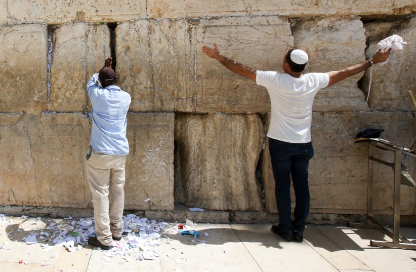 Man prayers while another cleans out notes from the Western Wall ahead of Rosh Hashana (photo credit: MARC ISRAEL SELLEM)