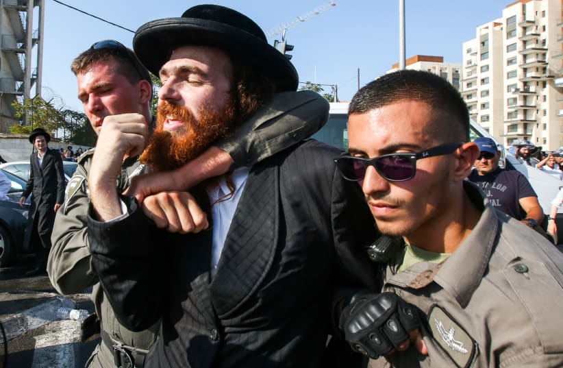 Police detain an ultra-Orthodox protestor at a violent anti-conscription protest in Jerusalem, September 17, 2017. (photo credit: MARC ISRAEL SELLEM)